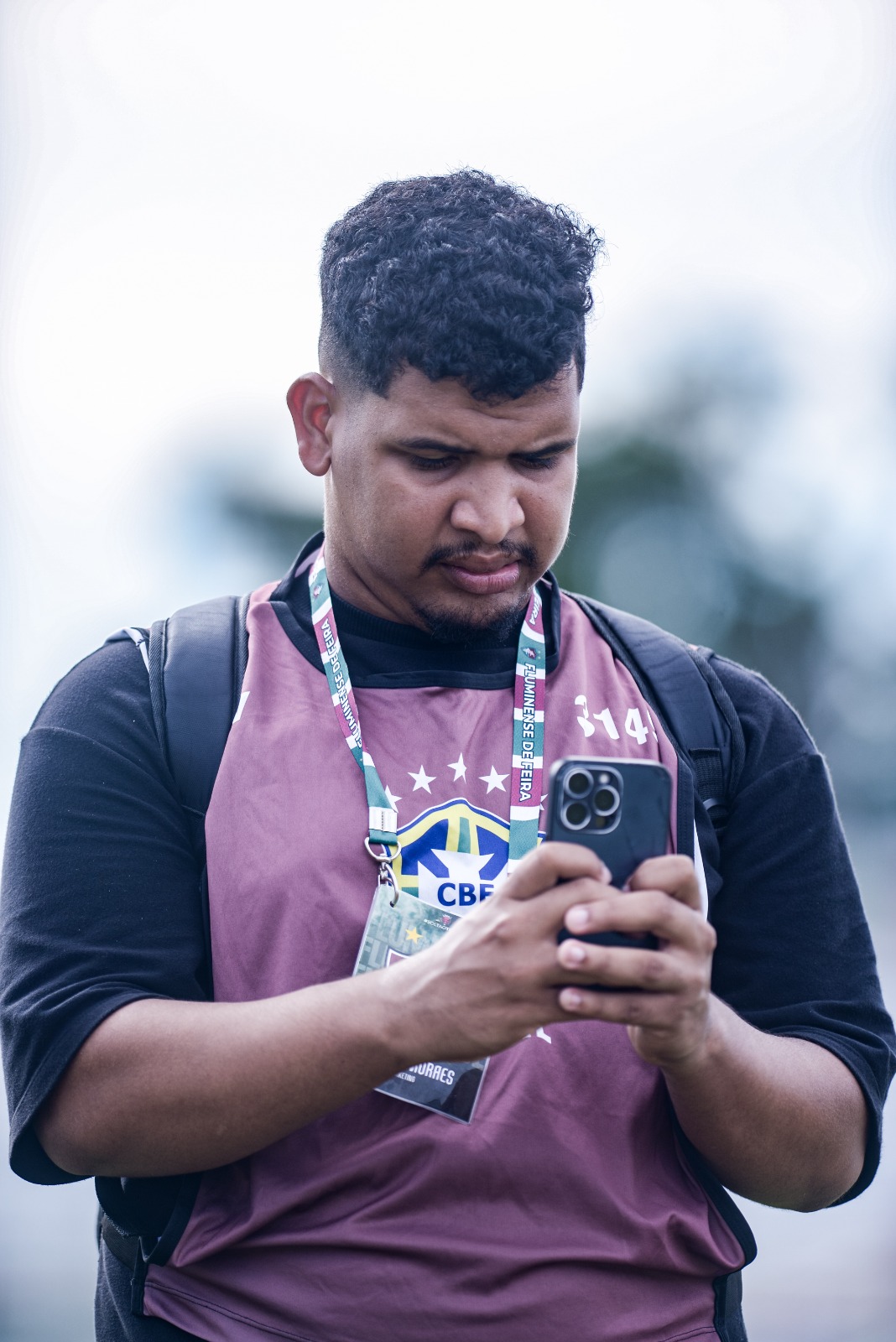 Samuel Moraes credenciado com colete do Fluminense de Feira usando o celular em campo