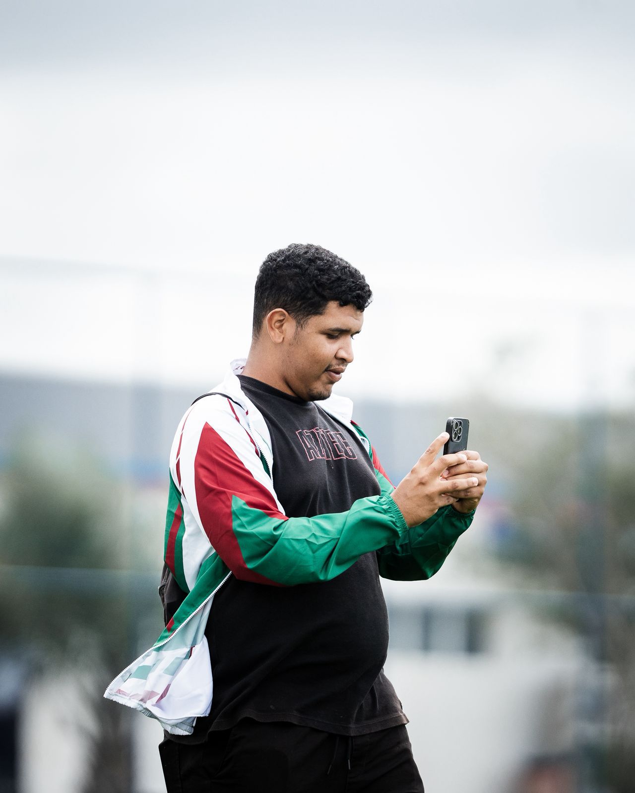 Samuel Moraes gravando com o celular durante treino, vestindo jaqueta do clube